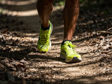 Close-up of trail runner's feet on dry, dusty forest path, dappled sunlight, high-contrast.