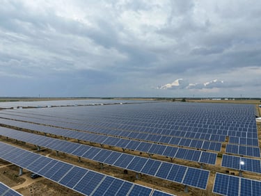 Wide-angle aerial shot of a massive solar farm stretching to the horizon under a dramatic overcast sky, steel blue tones, 35mm.