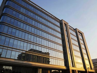 Sleek commercial office building exterior with glass facade reflecting golden-hour sunlight, wide-angle architectural shot, rich royal blue and gold accents