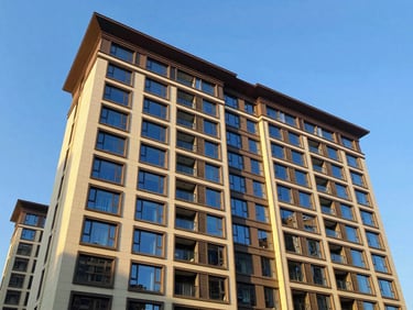 Modern residential apartment building with large windows under a clear blue sky, sunlit architectural exterior, wide-angle lens, rich royal blue and gold accents