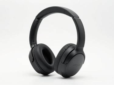 Front-on studio shot of premium wireless over-ear headphones in matte black on a white background, bright diffused studio lighting, full product detail, clean neutral surface