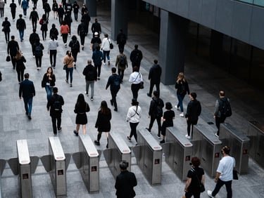 High-angle shot of organized crowd flow passing through modern digital turnstiles, cool daylight, precise architectural alignment.