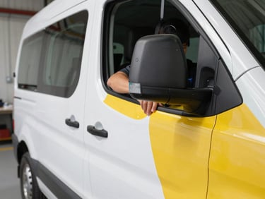 Close-up of a technician meticulously applying vinyl wrap to a fleet vehicle, crisp details of the vinyl edge, industrial workshop photography, bright clean daylight
