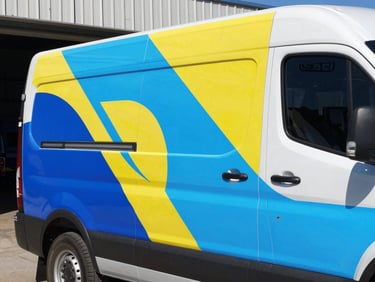 Close-up of a vibrant, professionally installed fleet vehicle wrap, showcasing sharp graphics and seamless application on a truck, industrial workshop background, bright clean daylight, crisp details, saturated corporate colors, sharp focus, 35mm lens