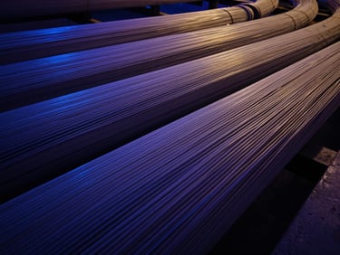 Wide shot of fiber optic cables bundled together, abstract patterns, deep blues and purples, industrial environment.