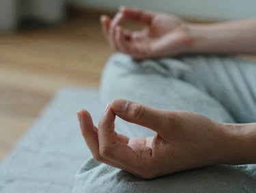 Close-up of hands resting in a meditative mudra on soft linen fabric, diffused natural light, muted earth tones, shallow depth of field.