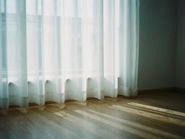Gentle morning sun filtering through a sheer white curtain onto a clean studio floor, creating a soft, peaceful, and airy atmosphere.