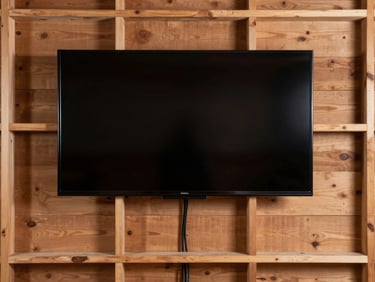 Straight-on architectural shot of a securely mounted heavy flat-screen television on a solid timber-framed wall, showing clean cable management and perfectly level alignment.