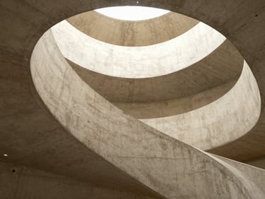 Dramatic low-angle interior shot of a brutalist concrete staircase winding upwards.