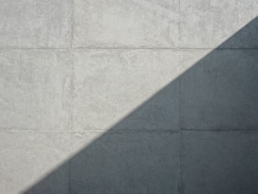 Abstract geometric pattern of light and shadow on a concrete wall, sharp lines, desaturated.