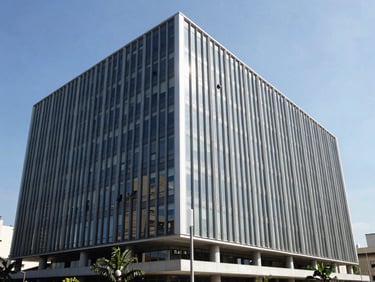 Exterior architectural shot of a modern, clean corporate office building in Porto Alegre, steel and glass facade, bright daylight, professional atmosphere.