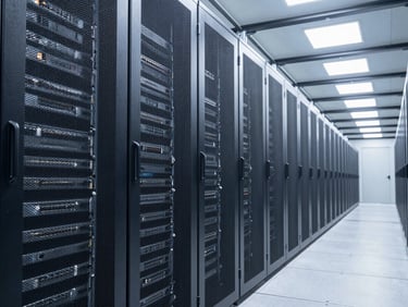 Wide environmental shot of a server farm interior, cool clinical white lighting on dense rack rows, camera positioned at the far left end of a long aisle, deep perspective lines receding right