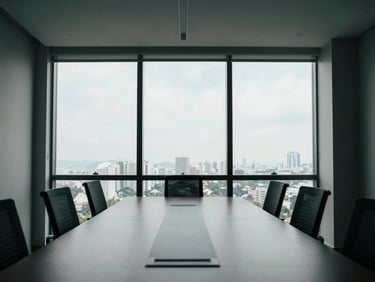 Wide environmental shot of a minimalist high-altitude corporate boardroom in São Paulo, cool natural window light, sharp architectural shadows, desaturated tones with deep green accents, 35mm