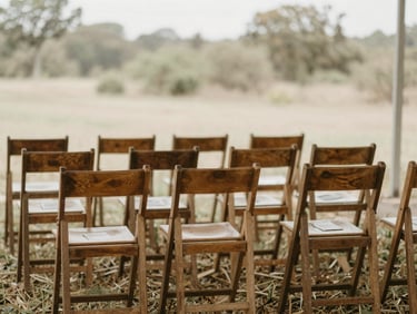 Wide shot of a quiet outdoor memorial service setup, simple wooden chairs, soft natural daylight, muted earth tones, shallow depth of field, serene natural background