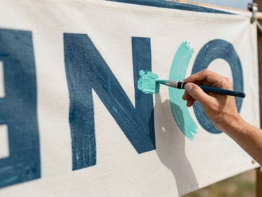 Close-up of artist hands painting a custom decorative banner on thick canvas, visible brushstrokes and teal paint textures