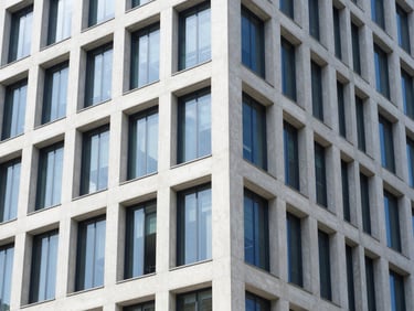 A wide architectural angle of a modern financial institution facade, sharp concrete and glass lines, cool-toned morning window daylight, deep navy and crisp white tones, sharp focus, 50mm lens.
