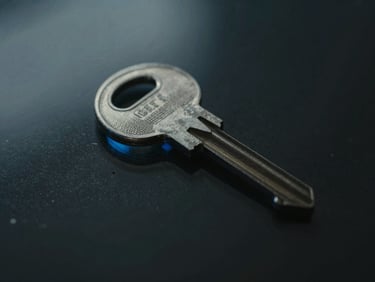 Macro close-up of a high-end physical steel key resting on dark glass, sharp blue reflections, moody lighting