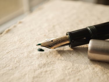 A close-up of a classic fountain pen nib resting on heavy textured cream paper, soft natural window light casting gentle shadows, elegant and quiet editorial atmosphere.