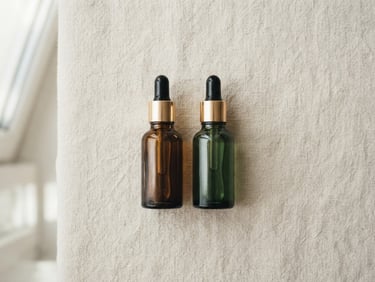 Overhead minimalist flat-lay of glass dropper bottles on a textured soft cream surface, soft natural window light, muted emerald tones