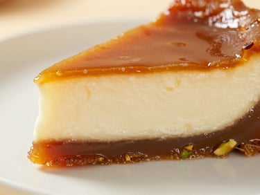 Macro shot of a slice of caramelized kazandibi dessert, showing the dark golden-brown caramelized bottom and the creamy white interior, soft warm side-light.