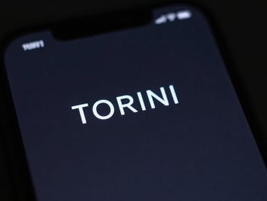 Macro close-up of a smartphone screen displaying a minimal TORINI launcher UI, deep charcoal background, electric blue accents, moody studio lighting.