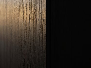 Macro detail shot of a seamless wood joint, dark textured wood veneer, low-key dramatic side-lighting, razor-sharp focus
