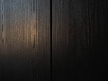 Macro architectural detail of continuous dark wood grain pattern across two cabinet doors, soft side lighting