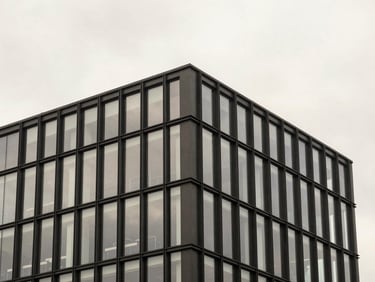 Exterior facade of a modern commercial building, blackened steel and glass, overcast sky, sharp details.