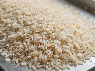 Overhead close-up of long-grain basmati rice spread across a flat sorting surface in a grading facility, natural daylight, cream-white grains showing length uniformity
