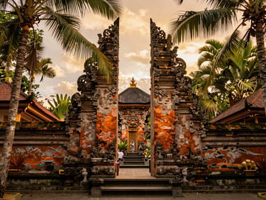 Warm golden-hour shot of a traditional Balinese stone temple gateway framed by tropical palm leaves, rich saturated tones.