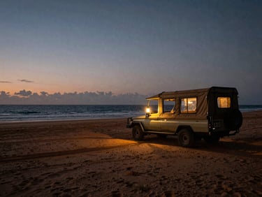 Atmospheric twilight shot of a luxury canvas safari outpost pitched on a remote, wild beach in Madagascar, a single warm lantern glowing inside, vast ocean backdrop.