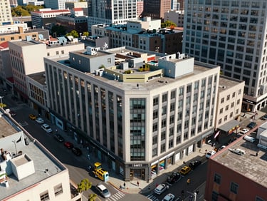 Overhead aerial framing of a mixed-use urban corner lot, three-storey building with ground-floor retail openings, flat daylight, surrounding block context, no people