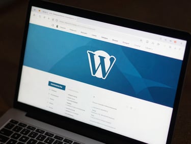 Close-up overhead view of a WordPress admin dashboard on a dark monitor, keyboard partially visible at the bottom edge, cool studio lighting