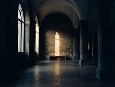Cinematic low-key photography of a quiet, empty architectural space with soft golden-hour light cutting through deep shadows, 35mm film grain, elegant and contemplative