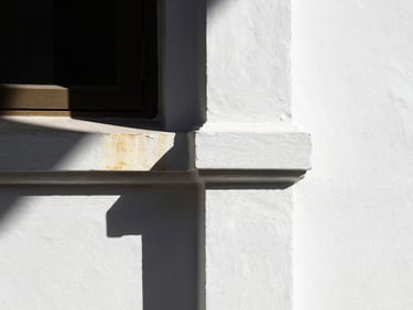 Sunlight hitting a perfectly smooth white painted wall, sharp corner detail, high-contrast architectural photography with subtle gold reflection