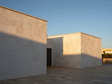 Vista simétrica de una villa minimalista en la Costa del Sol, hormigón visto y piedra caliza bajo luz de atardecer, sombras limpias.