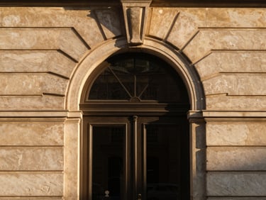 Elegant architectural detail of a European embassy doorway, stone arch, warm golden-hour daylight.