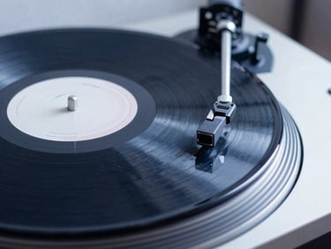 Close-up of a vintage vinyl record spinning on a turntable, soft studio lighting, deep blue and white tones, shallow depth of field, 35mm.