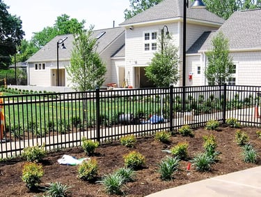 Black aluminum fence installed around a landscaped garden and residential building in Bear DE