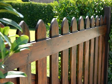 Traditional brown stained wooden picket fence in a lush green backyard Middletown DE.