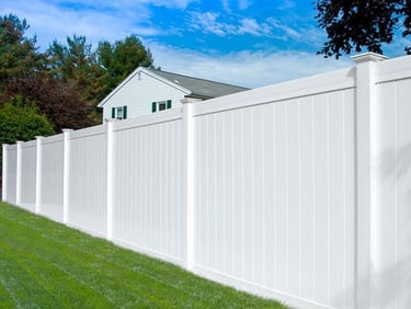 White vinyl privacy fence installed in a green suburban backyard for home security.