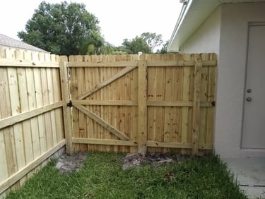 A newly installed natural wood privacy fence with a gated entrance in a Bear DE residential backyard