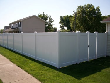 White vinyl privacy fence and matching gate installed along a Middletown DE property lawn.