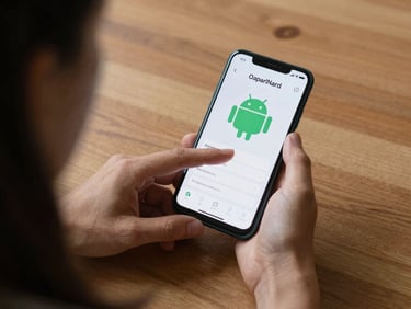 Over-the-shoulder view of a hand tapping a productivity app on an Android phone, sitting on a wooden desk in flat daylight, no clutter