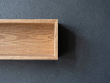 Close-up of high-quality warm wood accents against a deep slate wall, soft natural daylight, 35mm lens.