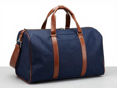 Navy blue canvas weekender duffel bag with brown leather handles, arranged neatly on a light gray surface, studio lighting