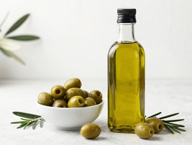 A bottle of green extra virgin olive oil next to a bowl of fresh olives and a rosemary sprig, diffused natural daylight