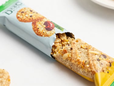 Close-up of a highly processed industrial snack bar package being torn open, showing artificial textures, bright daylight.