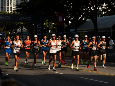 High-contrast shot of marathon runners crossing the finish line at the BYD Singapore Marathon, golden hour highlights.
