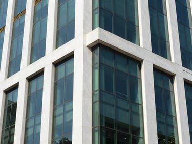 Sleek architectural detail of a modern glass and steel office building in Lahore, bright daylight, reflections of blue sky, 35mm lens.